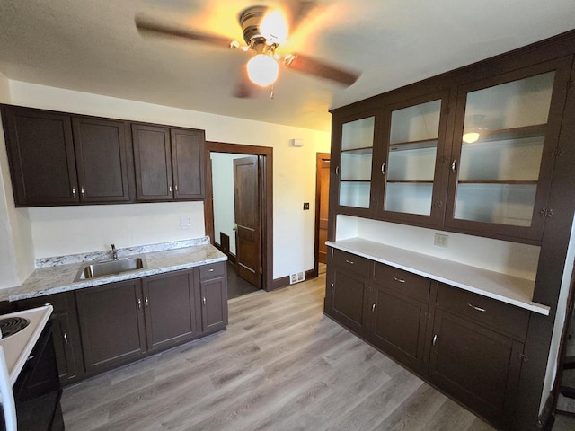 kitchen with range with electric cooktop, light wood-style flooring, light countertops, dark brown cabinets, and a sink