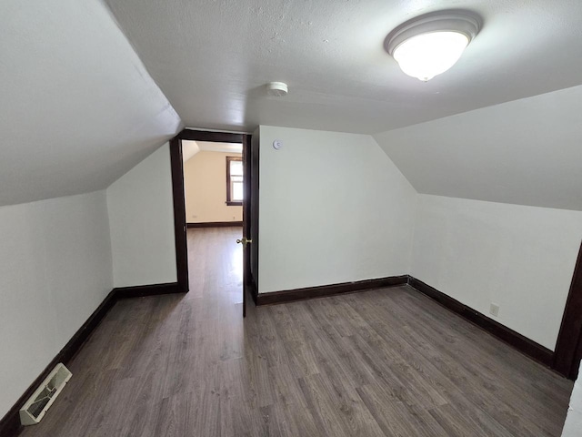 bonus room with dark wood-type flooring, lofted ceiling, visible vents, and baseboards