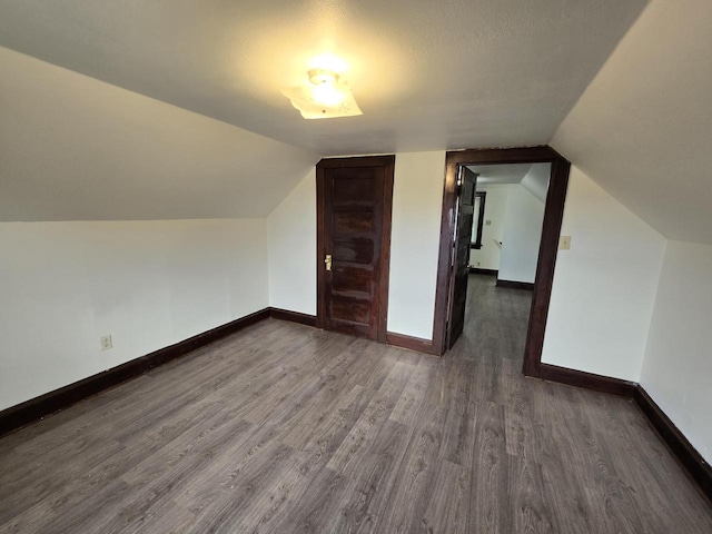 bonus room featuring vaulted ceiling, baseboards, and dark wood finished floors