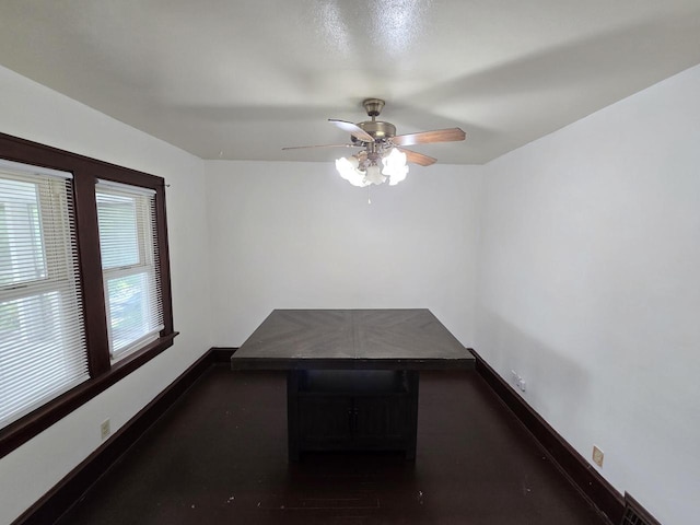 unfurnished dining area featuring a ceiling fan and baseboards