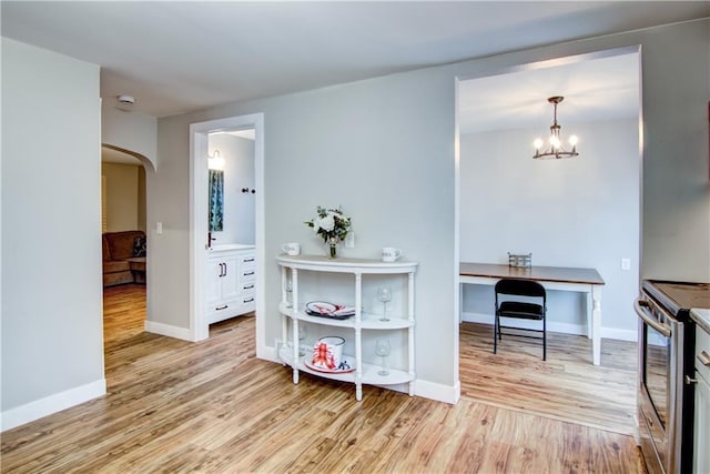 rec room with arched walkways, light wood-type flooring, a notable chandelier, and baseboards