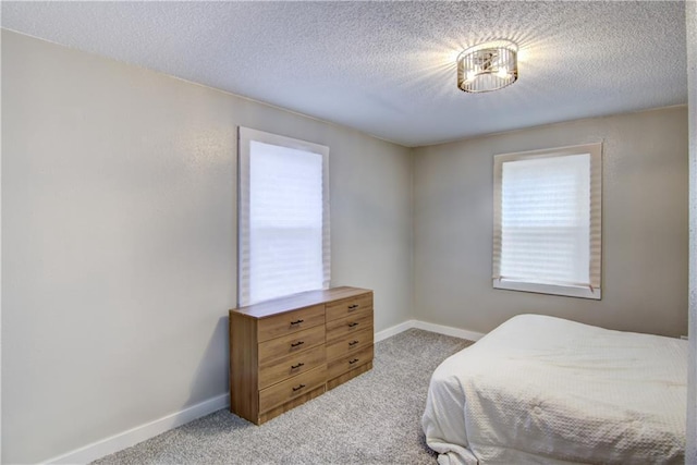 carpeted bedroom featuring a textured ceiling and baseboards