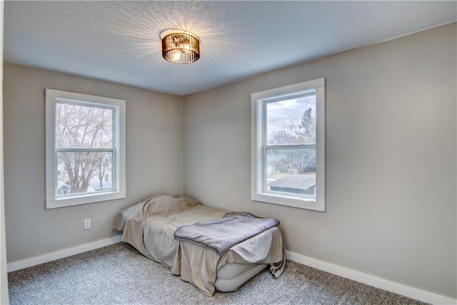 carpeted bedroom with a textured ceiling and baseboards