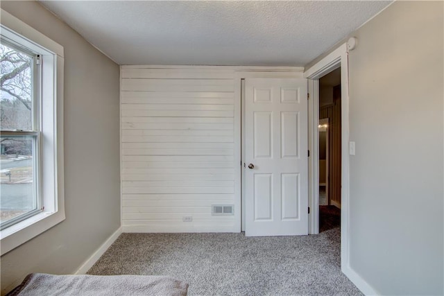 spare room with carpet floors, baseboards, visible vents, and a textured ceiling