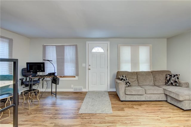 living room featuring wood finished floors, visible vents, and baseboards