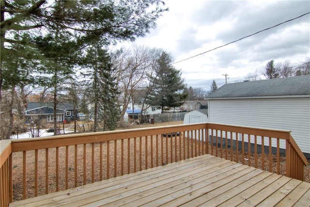 wooden terrace featuring a shed, fence, and an outbuilding