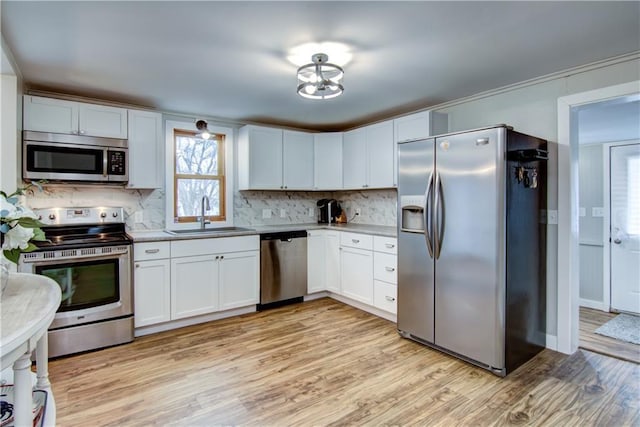 kitchen featuring light wood-type flooring, backsplash, stainless steel appliances, and a sink