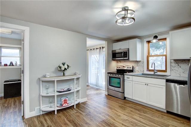 kitchen featuring light wood-style floors, tasteful backsplash, stainless steel appliances, and a sink