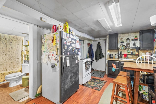 kitchen featuring electric stove, light countertops, parquet flooring, and freestanding refrigerator