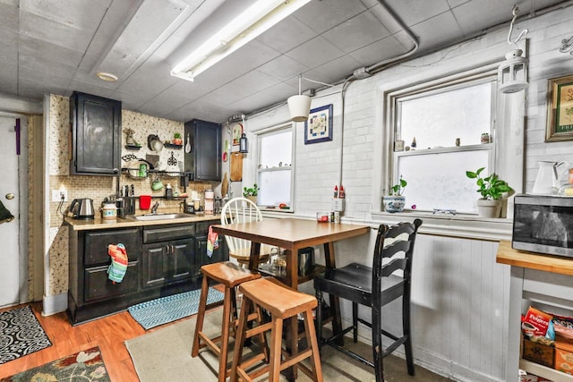 kitchen featuring light wood finished floors, decorative backsplash, light countertops, and a sink