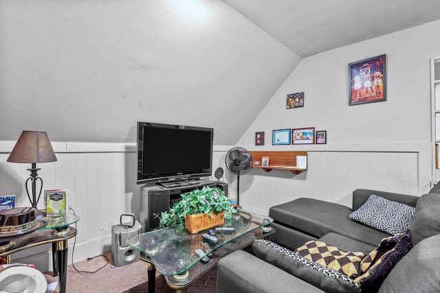 carpeted living area with wainscoting and vaulted ceiling