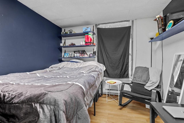 bedroom featuring a baseboard heating unit and wood finished floors