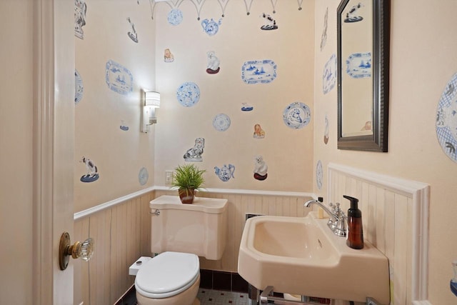 bathroom with toilet, a sink, and wainscoting