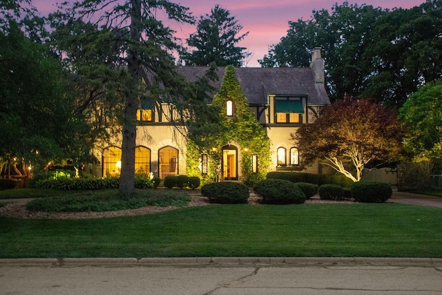 tudor home featuring a chimney and a front yard