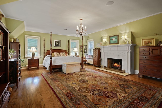 bedroom featuring baseboards, ornamental molding, dark wood-style flooring, an inviting chandelier, and a fireplace