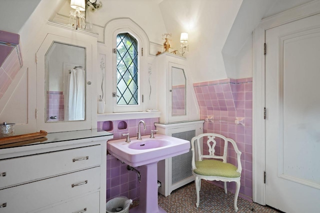 bathroom with a wainscoted wall, a sink, tile patterned flooring, and tile walls