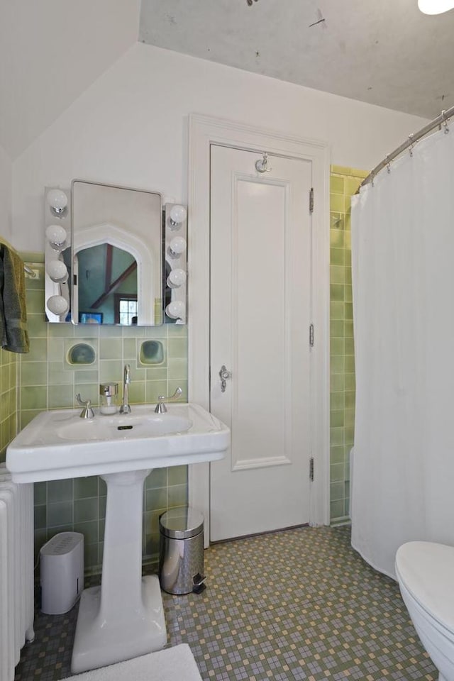 full bathroom with tile walls, toilet, radiator heating unit, vaulted ceiling, and a shower with curtain