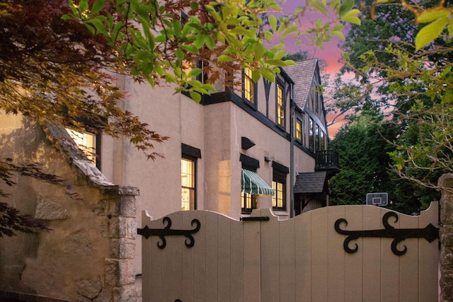 property exterior at dusk with a fenced front yard and stucco siding