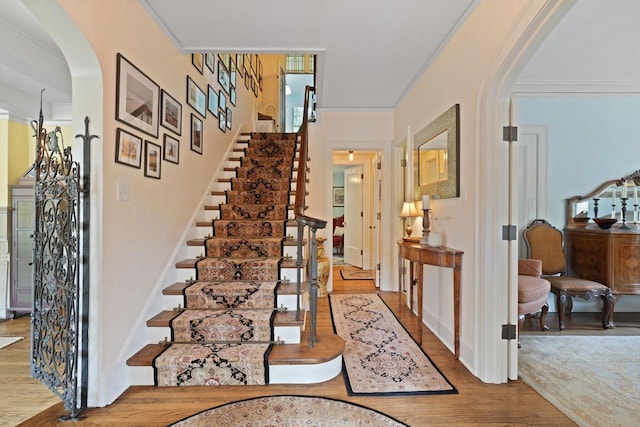 entrance foyer featuring ornamental molding, arched walkways, and wood finished floors