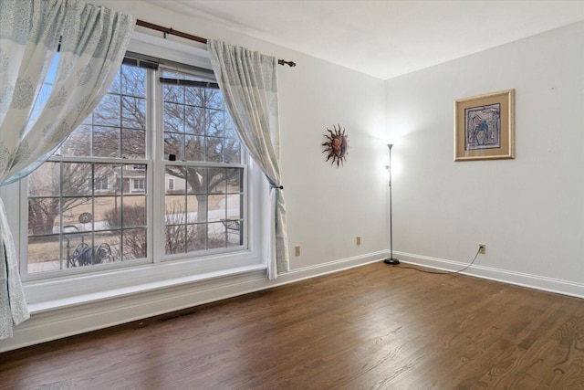 empty room featuring visible vents, baseboards, and wood finished floors