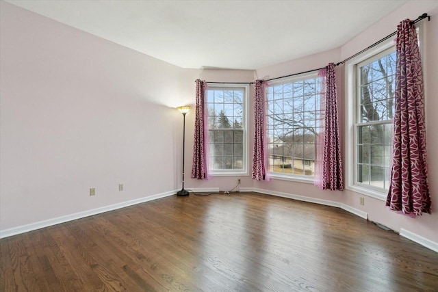 unfurnished room featuring dark wood-style floors and baseboards