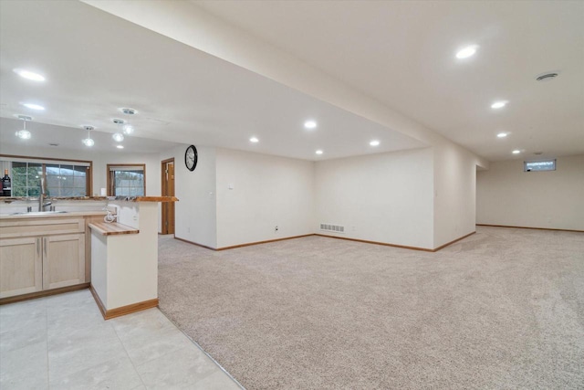 below grade area with recessed lighting, visible vents, a sink, and light colored carpet