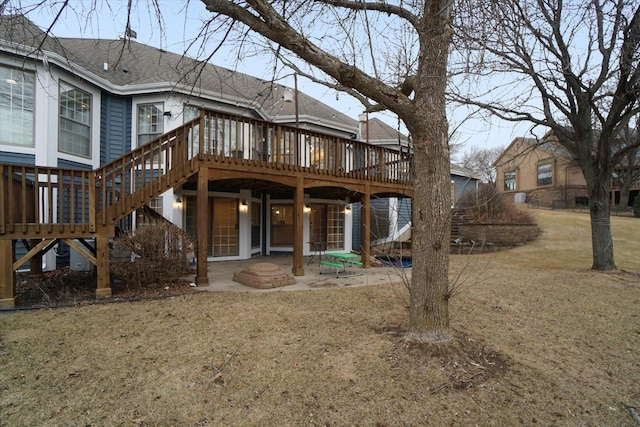 rear view of property with a shingled roof, a lawn, stairway, a patio area, and a deck