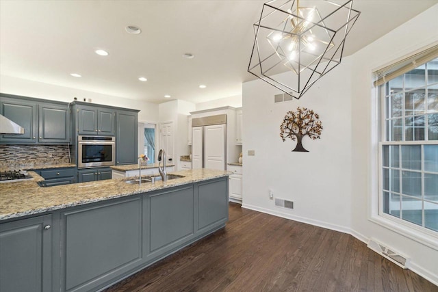 kitchen with stainless steel appliances, visible vents, a sink, and dark wood-style floors