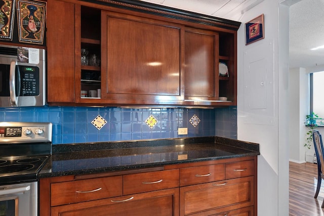 kitchen with dark stone countertops, decorative backsplash, appliances with stainless steel finishes, and brown cabinetry