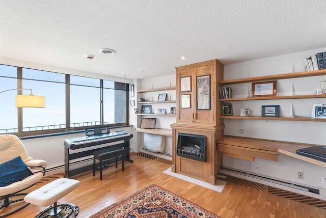 interior space featuring light wood finished floors, visible vents, a textured ceiling, and built in study area