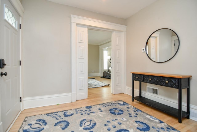 entryway with wood finished floors, visible vents, and baseboards