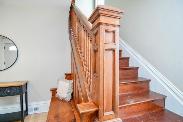 staircase with visible vents, baseboards, and wood finished floors