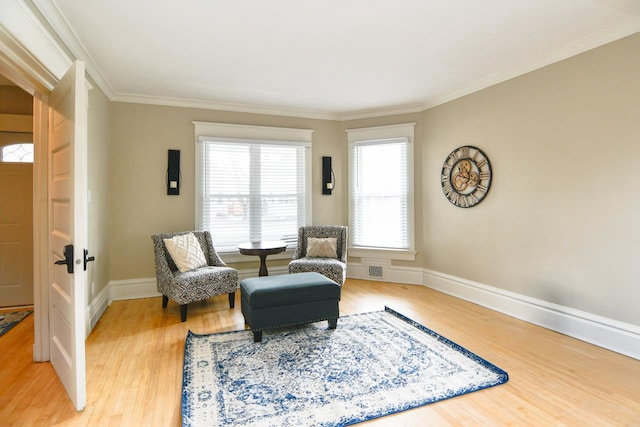 living area with light wood-style flooring, ornamental molding, and baseboards