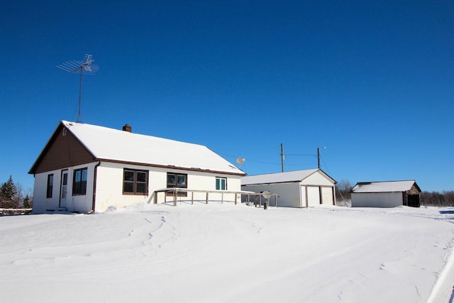 snow covered property featuring a garage and an outdoor structure