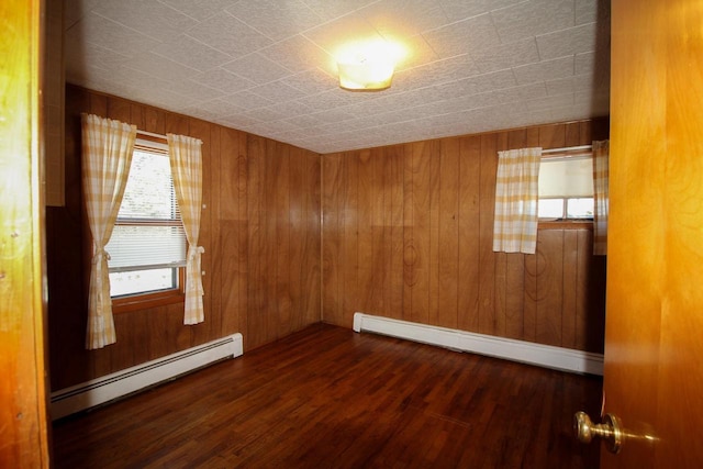 empty room with wood walls, baseboard heating, and wood finished floors