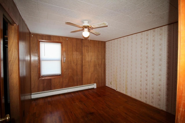 unfurnished room featuring ceiling fan, wood walls, baseboard heating, and wood finished floors