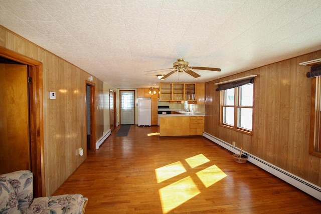 kitchen with wood walls, baseboard heating, wood finished floors, and freestanding refrigerator