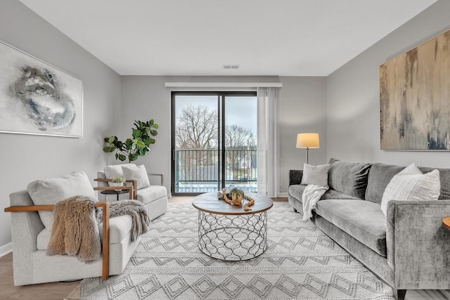 living room featuring light wood-type flooring, baseboards, and visible vents