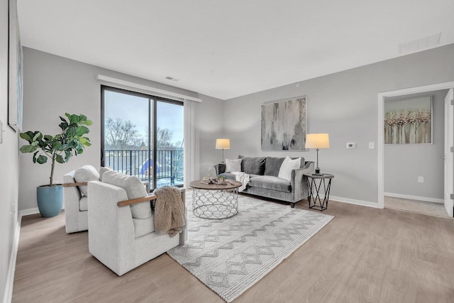 living room featuring light wood finished floors, visible vents, and baseboards