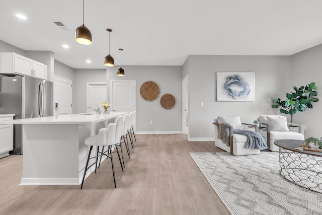 kitchen with baseboards, visible vents, white cabinets, light countertops, and light wood-style floors