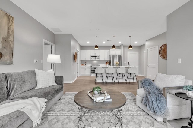 living area with recessed lighting, baseboards, and light wood finished floors