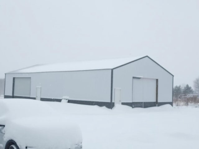 snow covered structure featuring an outbuilding