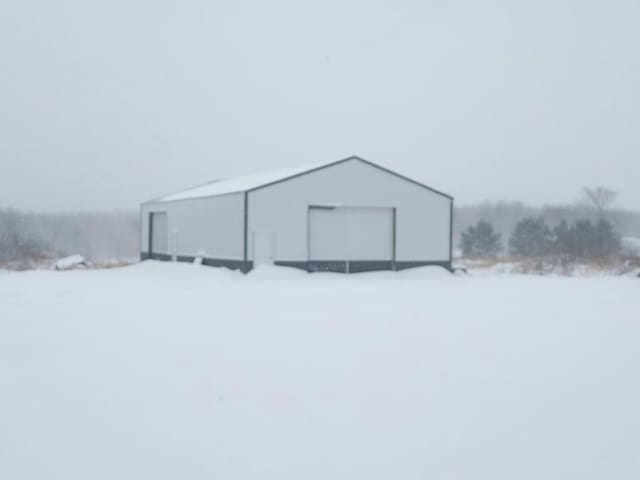 snow covered structure featuring an outbuilding and an outdoor structure