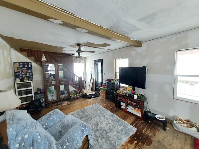 living area featuring stairs, ceiling fan, beamed ceiling, and wood finished floors