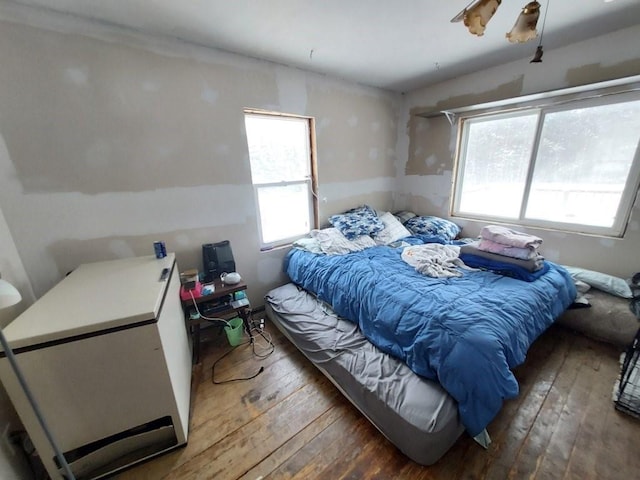 bedroom with hardwood / wood-style flooring and refrigerator