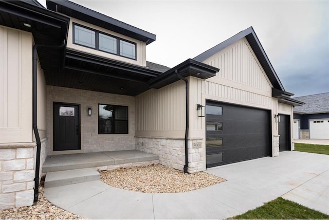 view of front of home featuring stone siding, board and batten siding, an attached garage, and driveway