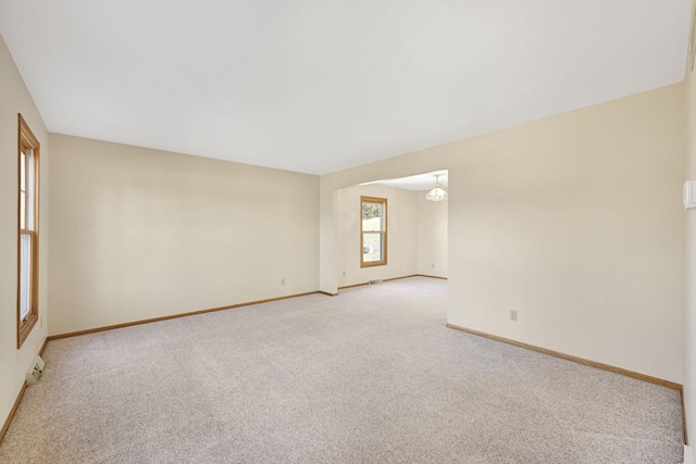 empty room featuring light colored carpet and baseboards