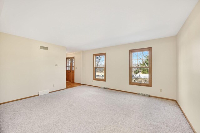 spare room featuring visible vents, baseboards, and light colored carpet