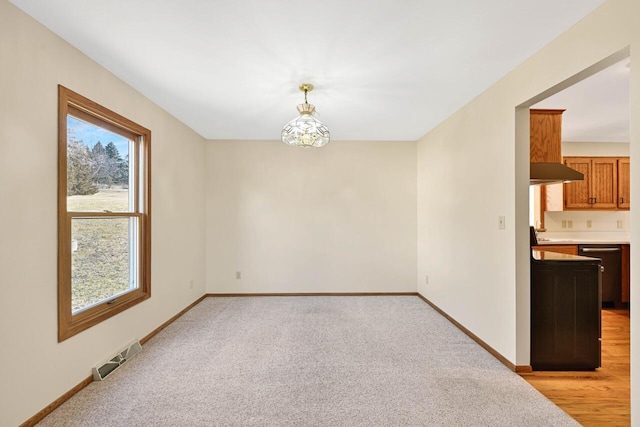 unfurnished dining area with visible vents, baseboards, and light carpet