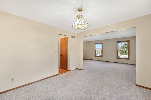 empty room featuring light colored carpet, visible vents, and baseboards